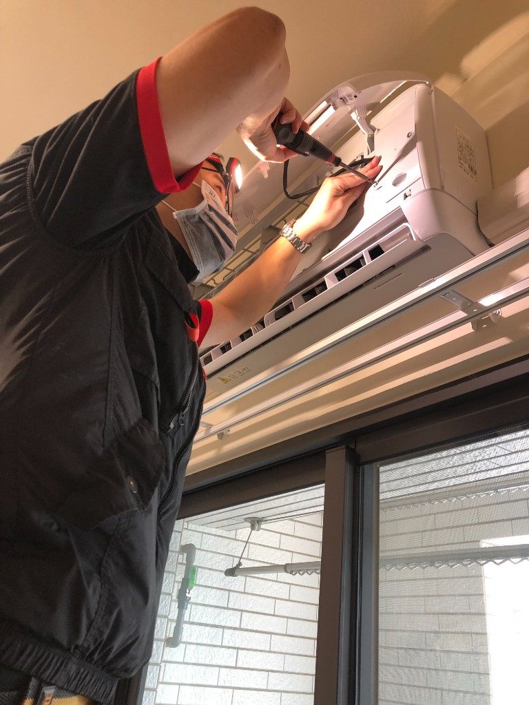 飛揚清洗技師以頭燈照明拆卸室內機零件