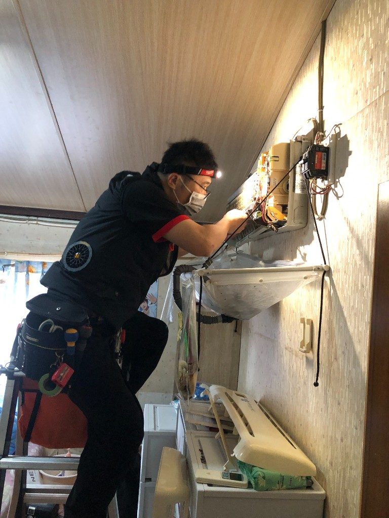 飛揚清洗技師戴頭燈清洗室內機，下方已裝接水罩